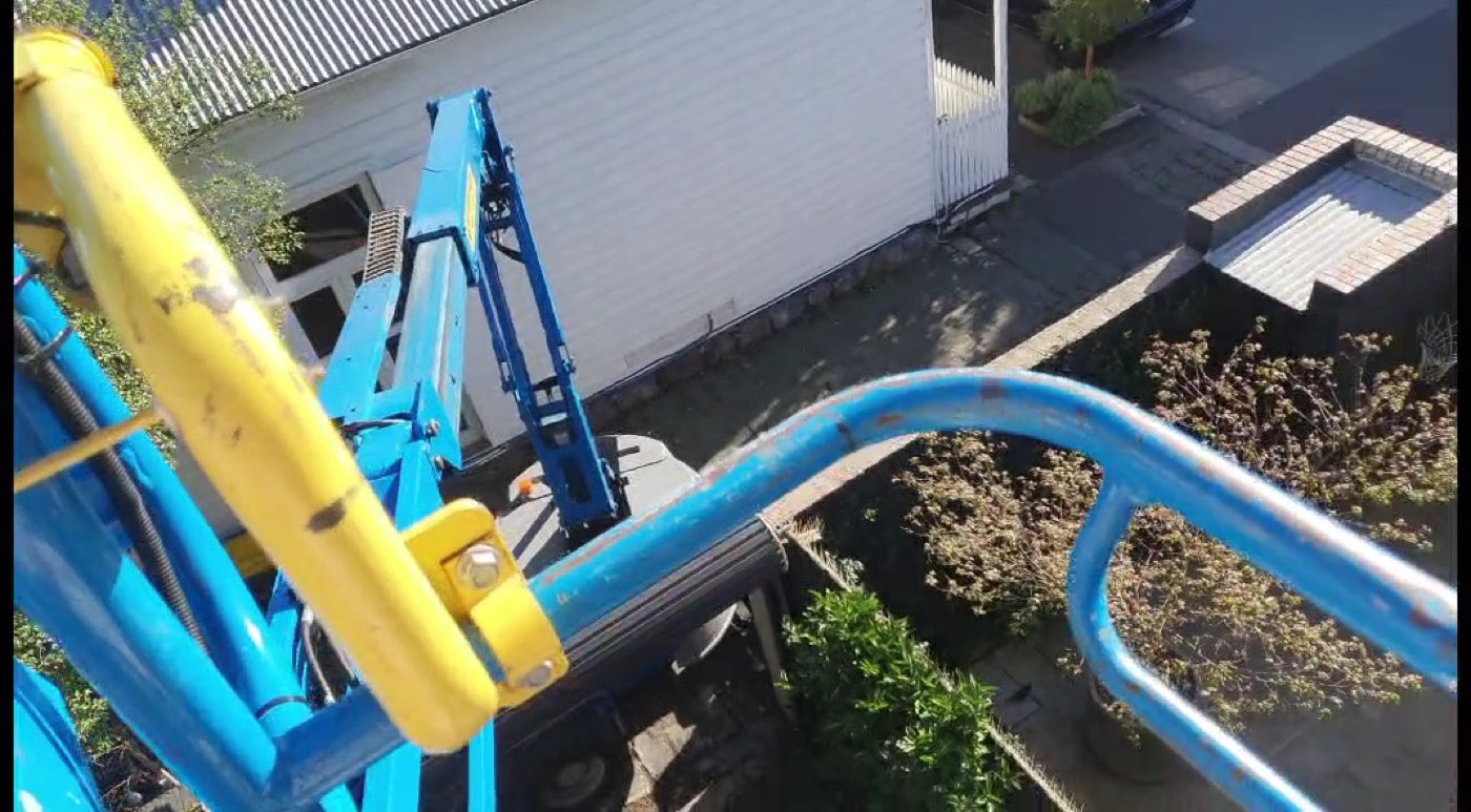 Looking down from a boom lift beside a weatherboard house