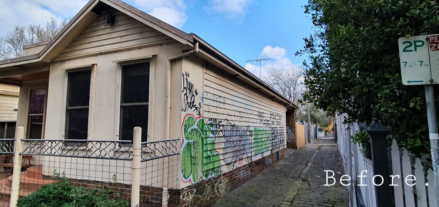 The side of the cottage before, covered in graffiti