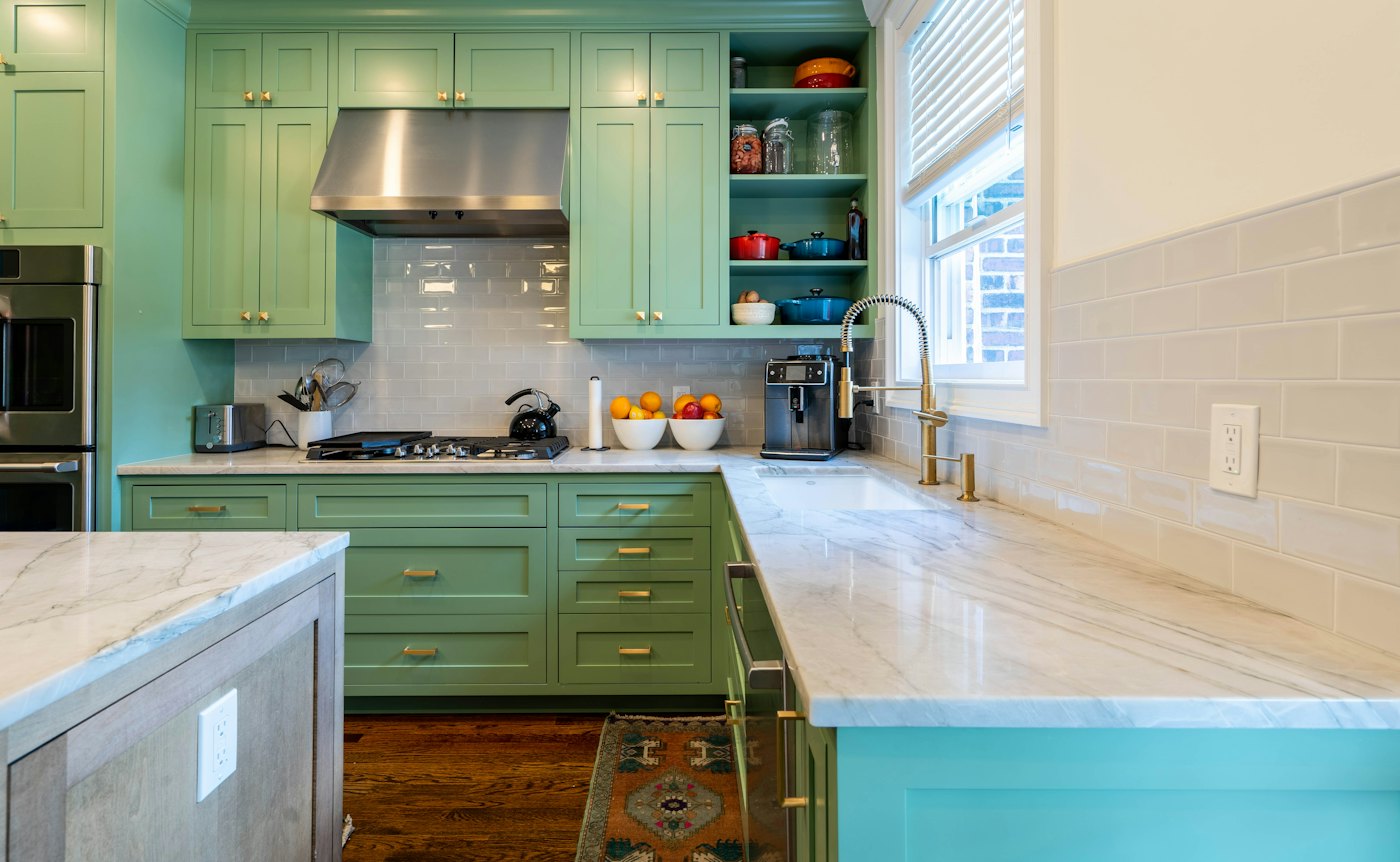 A kitchen with cabinets painted soft green
