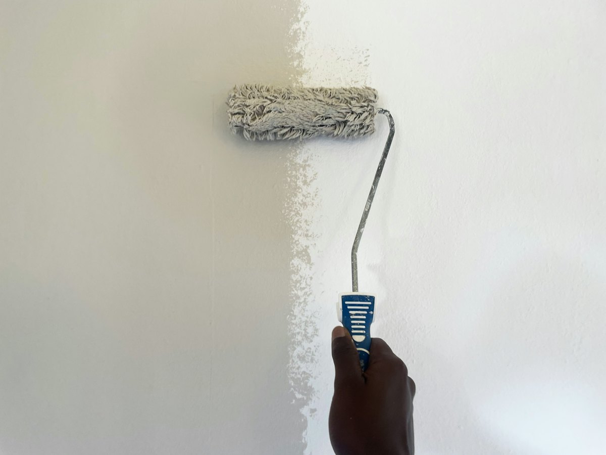 A roller putting a fresh coat on a repaired wall