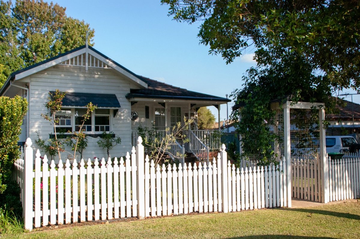 A white weatherboard house behind a picket fence